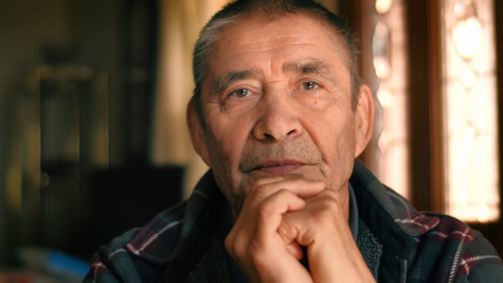 Serious, elderly immigrant thinking, looking at camera, closeup portrait.