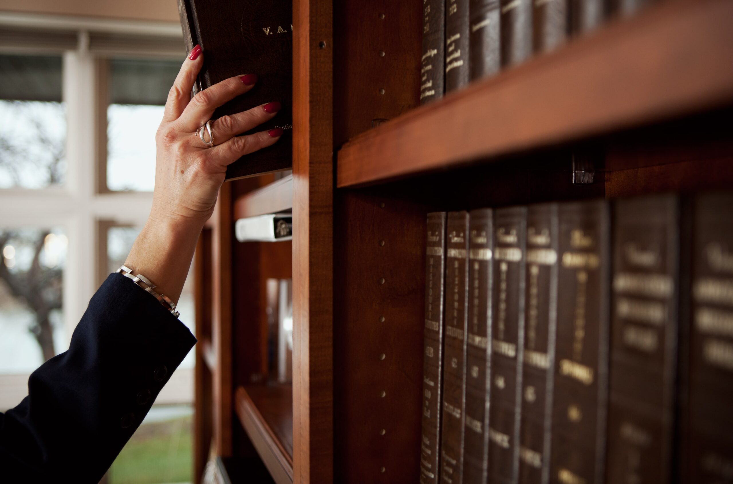 Hand removing book of legal resources from shelf