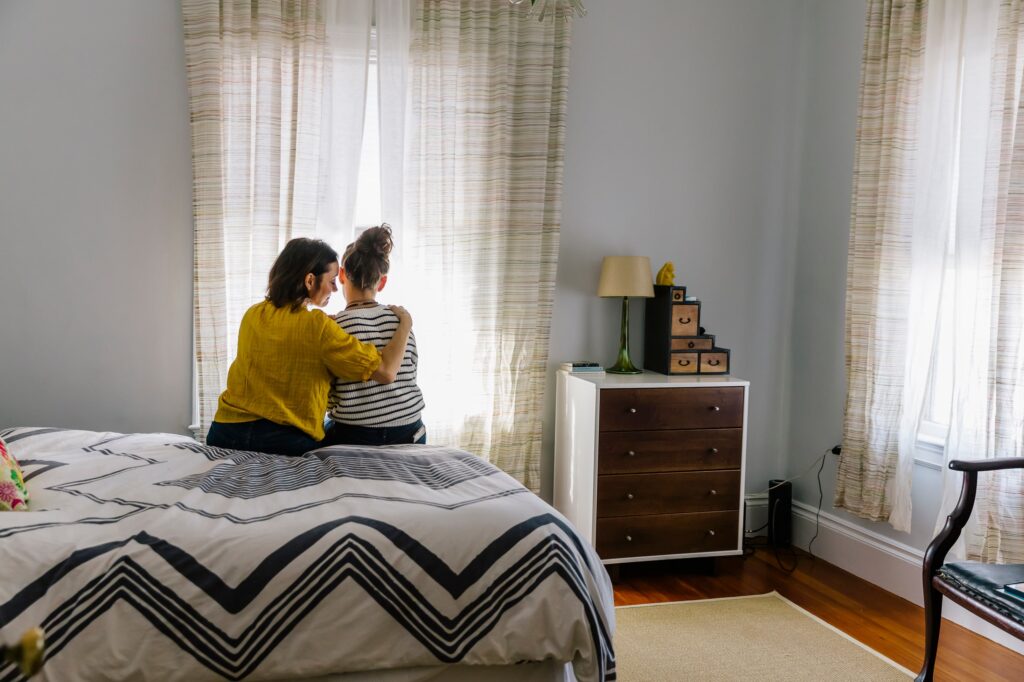 Mother And Teen Daughter Together Talking In Bedroom