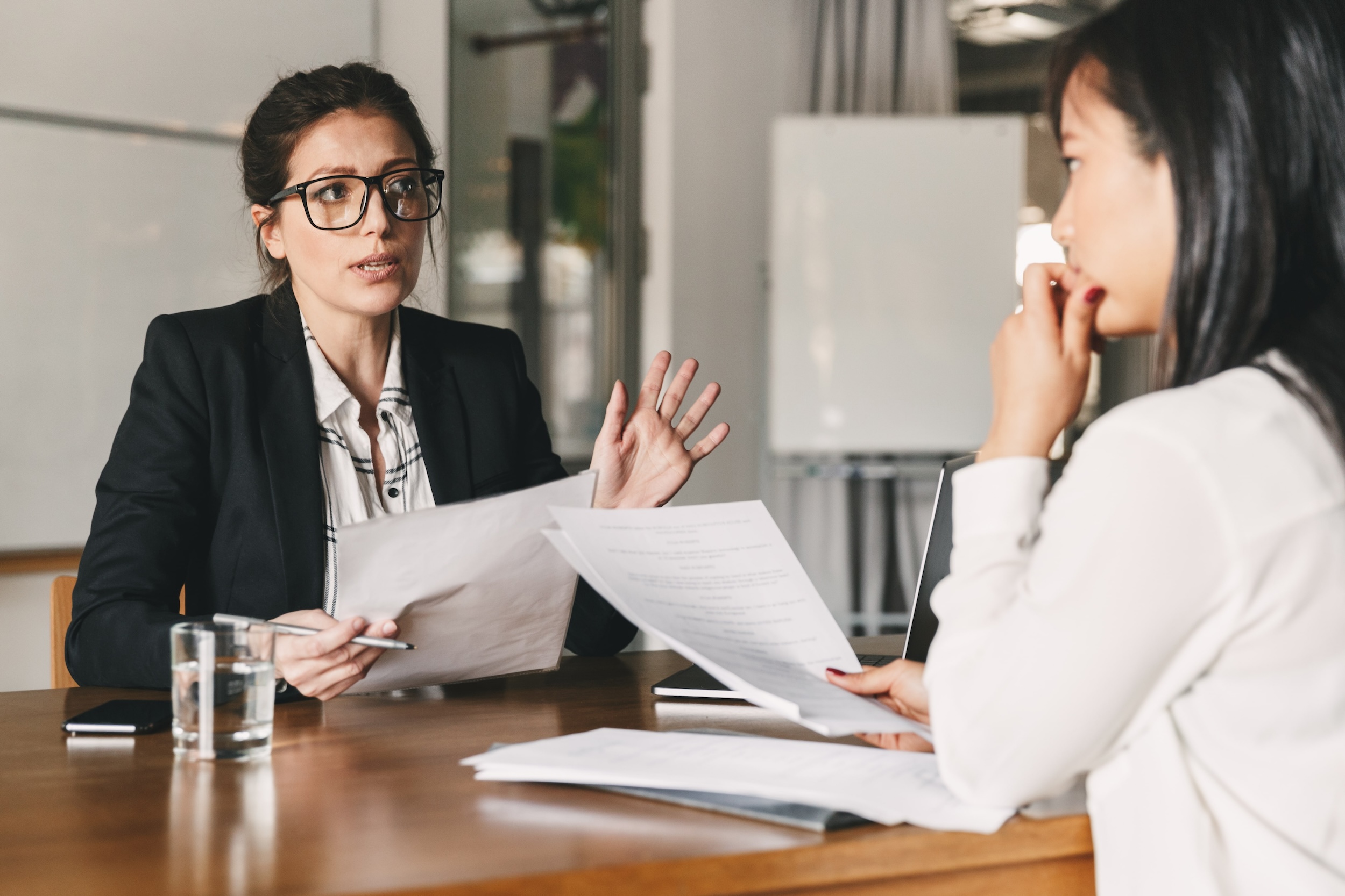 Image representing a female immigrant with a concerned expression speaking with lawyer.