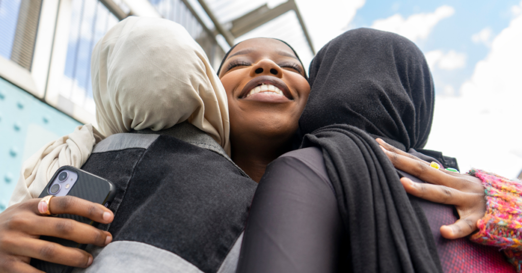 women wearing hijabs smiling and hugging
